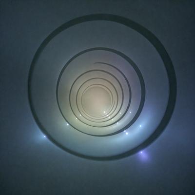 The primary subject of the image is a spiral tunnel, which is a large, curved structure. The tunnel is illuminated by a blue light, giving it a unique and captivating appearance. The setting is a dark, foggy environment, which adds to the mysterious and intriguing atmosphere of the scene. The visual style of the image is a combination of photo and digital art, creating a striking and visually appealing representation of the spiral tunnel. The colors and mood of the image are predominantly dark